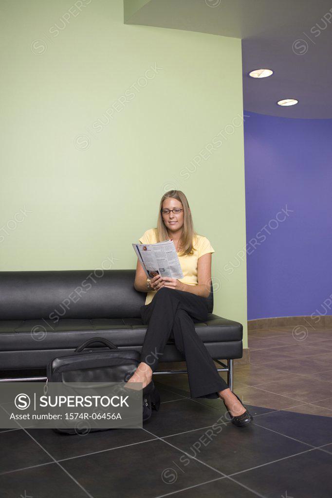Stock Photo: 1574R-06456A Businesswoman sitting on a couch reading a newspaper in an office