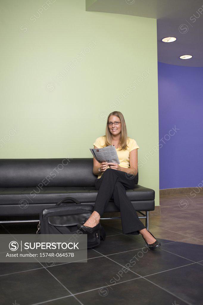 Stock Photo: 1574R-06457B Businesswoman sitting on a couch reading a newspaper in an office