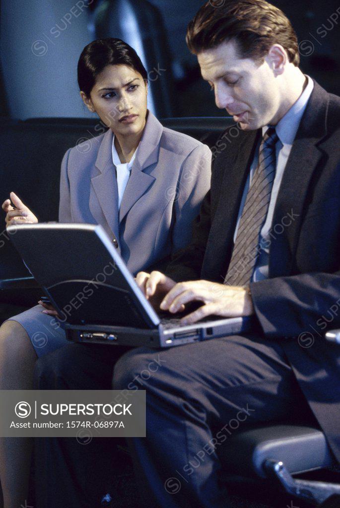Stock Photo: 1574R-06897A Side profile of a businessman and businesswoman sitting in front of a laptop
