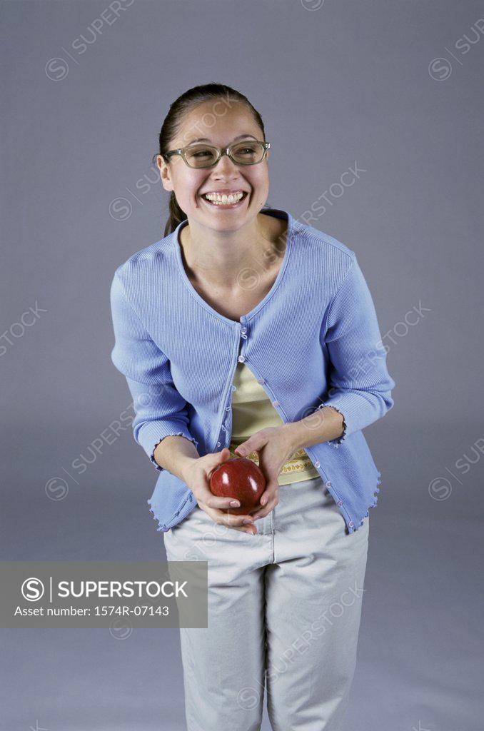 Stock Photo: 1574R-07143 Portrait of a teenage girl holding an apple smiling