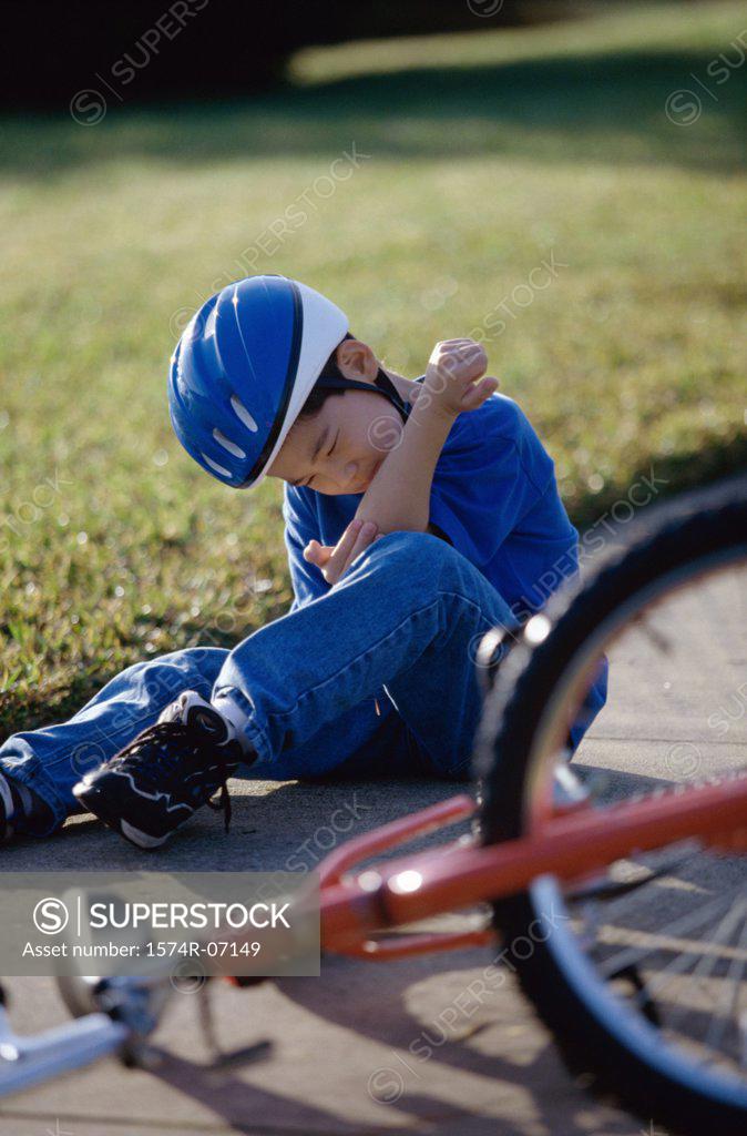 Stock Photo: 1574R-07149 Boy fallen from a bicycle holding his injured elbow