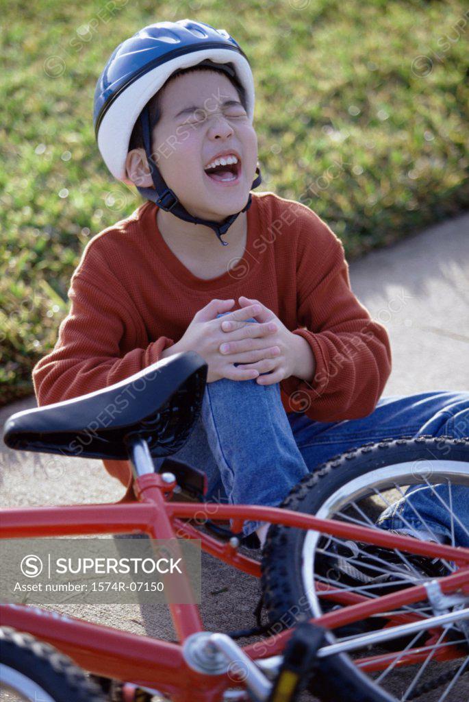 Stock Photo: 1574R-07150 Boy fallen from a bicycle holding his injured knee