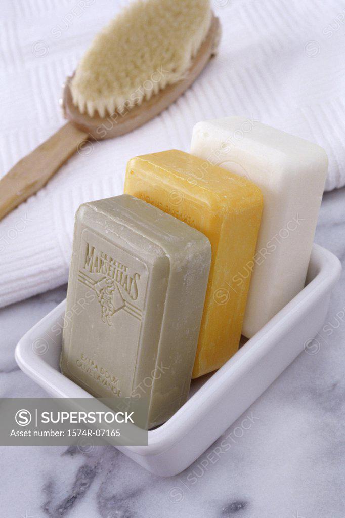 Stock Photo: 1574R-07165 Three soaps in a soap dish with a brush and towel