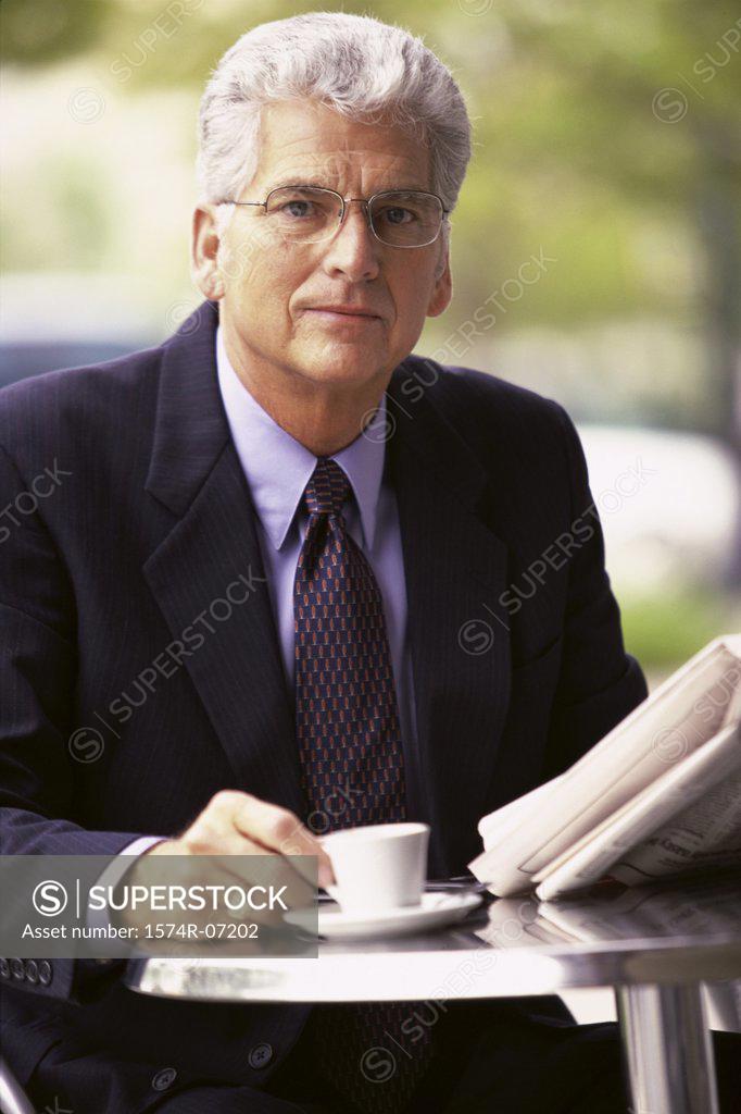 Stock Photo: 1574R-07202 Portrait of a businessman holding a newspaper and a cup of coffee