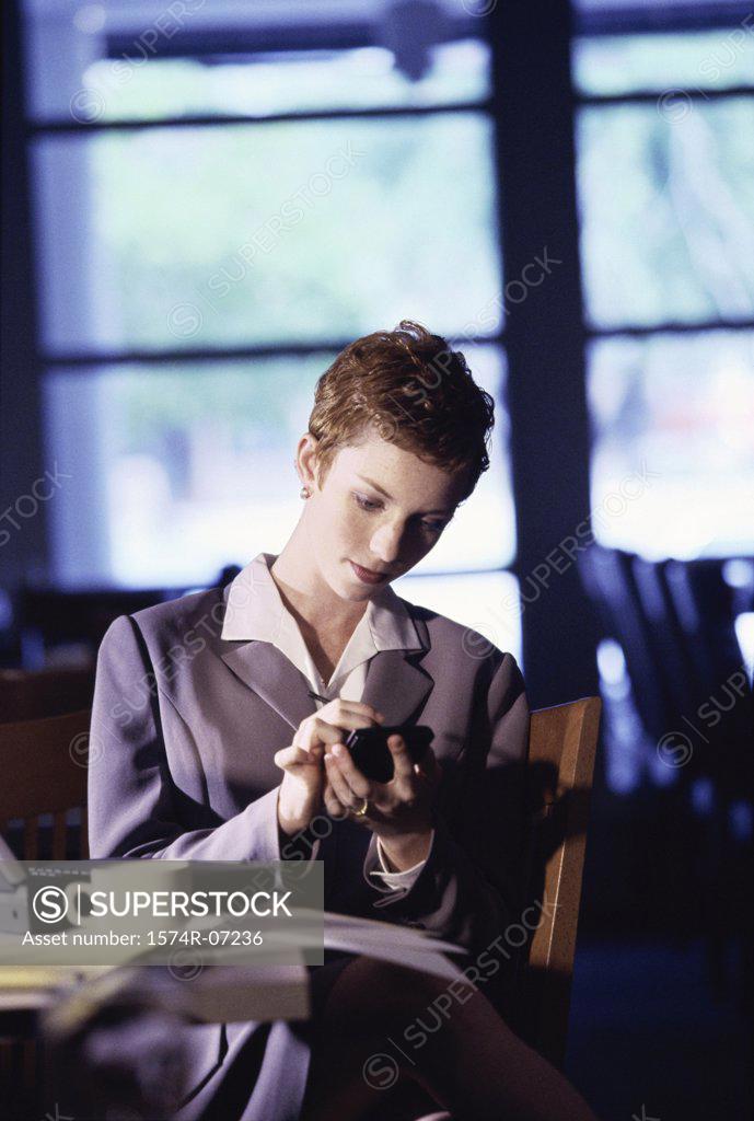 Stock Photo: 1574R-07236 Businesswoman sitting in a restaurant using a hand held device