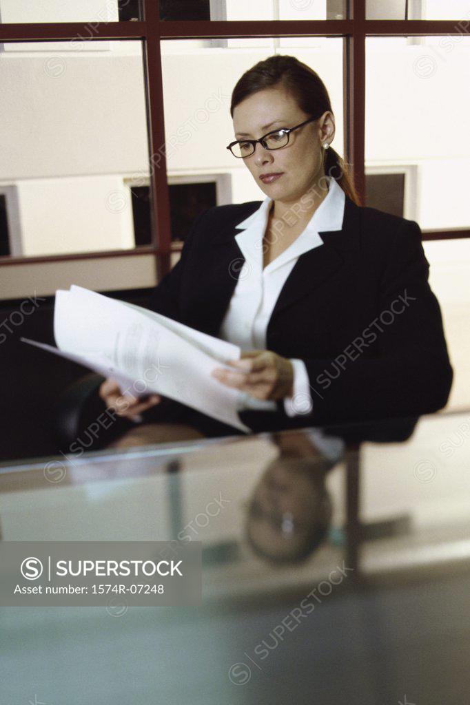 Stock Photo: 1574R-07248 Businesswoman seated at an office desk reading papers