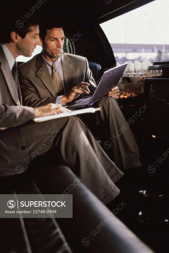 Stock Photo: 1574R-0949 Two businessmen using a laptop in a car