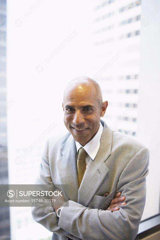 Stock Photo: 1574R-20179 Portrait of a businessman standing with his arms crossed in an office
