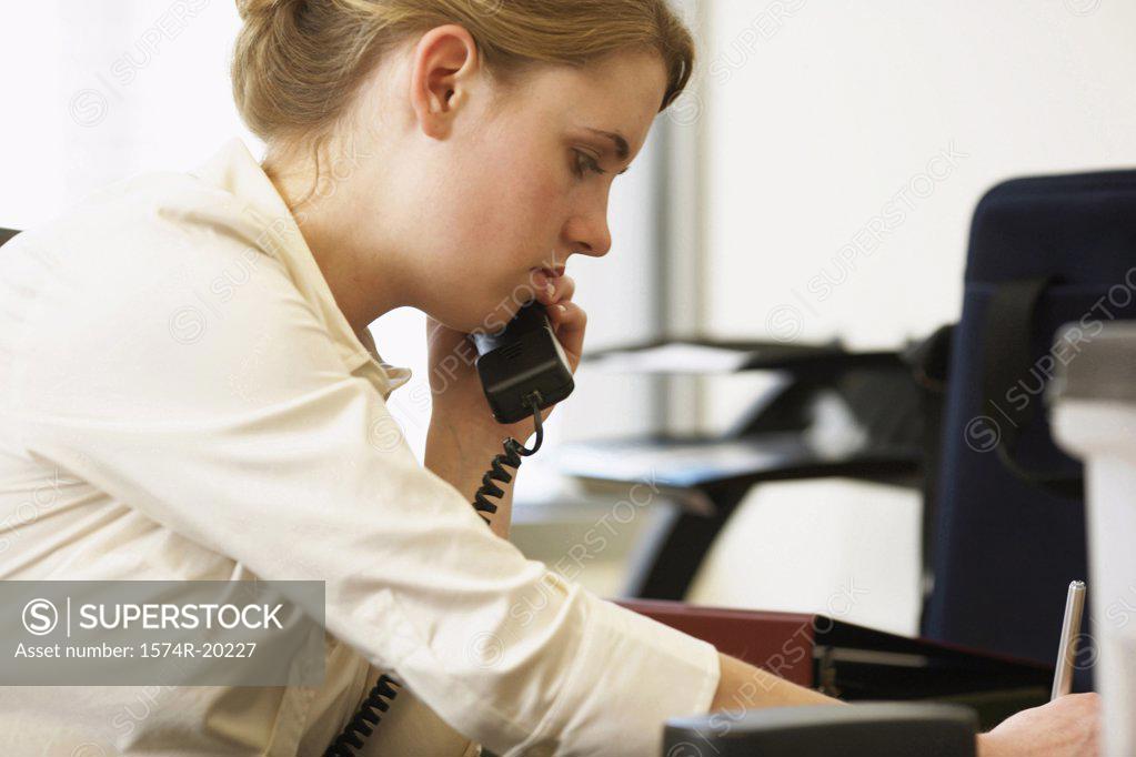 Stock Photo: 1574R-20227 Side profile of a businesswoman using a telephone in an office