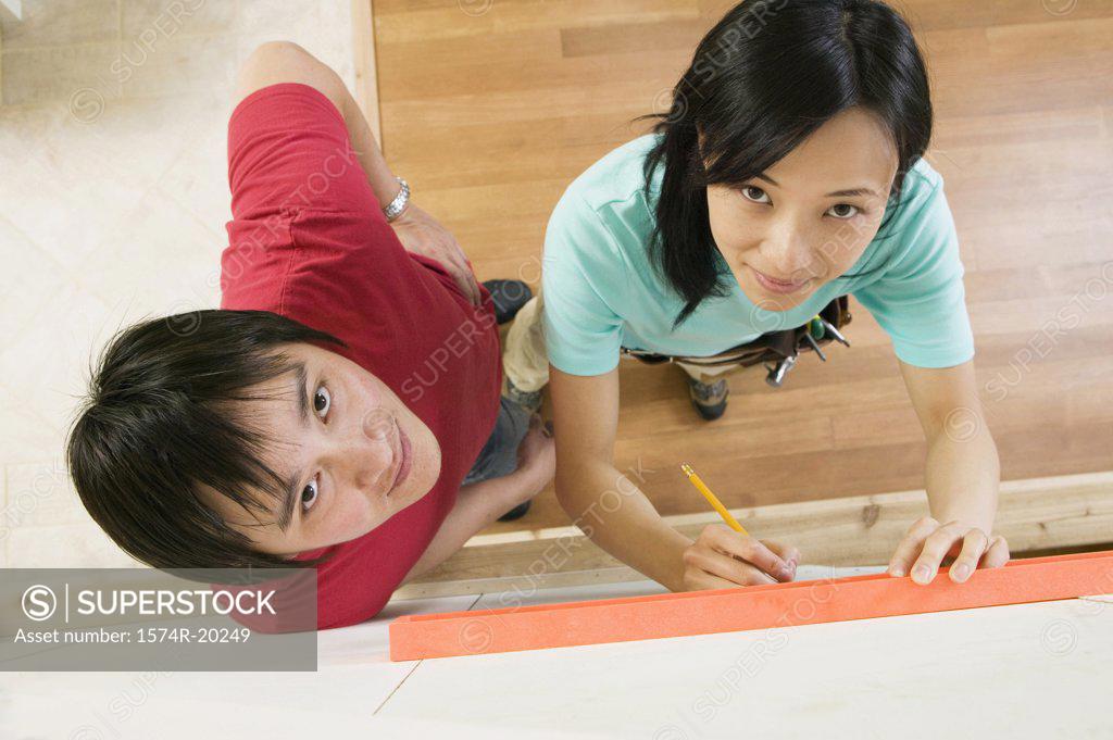 Stock Photo: 1574R-20249 High angle view of a young woman using a spirit level to mark on a wall with a young man standing beside her