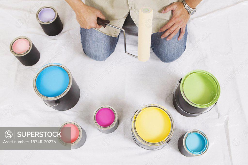 Stock Photo: 1574R-20276 High angle view of a man holding a paint roller with paint cans in front of him