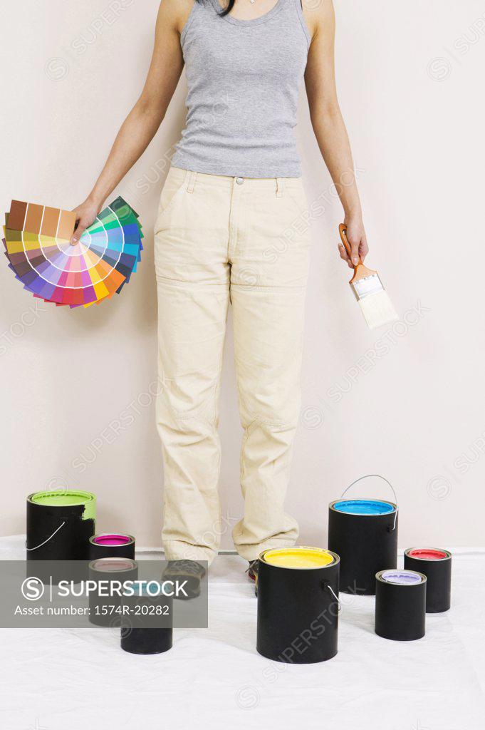 Stock Photo: 1574R-20282 Low section view of a young woman holding color swatches and a paintbrush