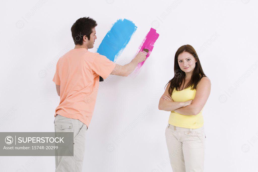 Stock Photo: 1574R-20299 Young man painting a wall with a young woman standing beside him