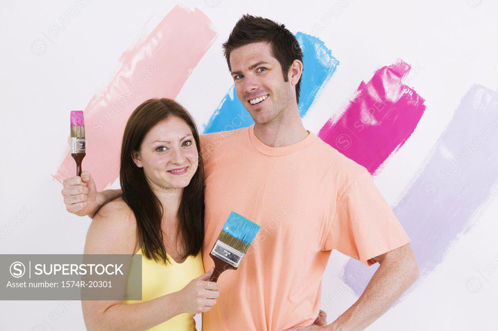 Stock Photo: 1574R-20301 Portrait of a young couple holding paintbrushes