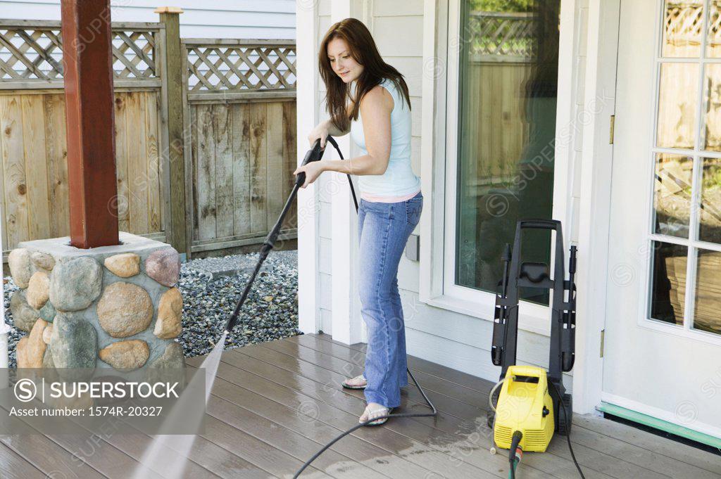 Stock Photo: 1574R-20327 Side profile of a young woman cleaning the porch of her house