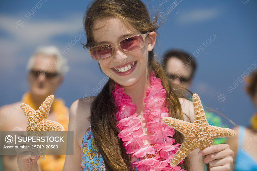 Stock Photo: 1574R-20580 Close-up of a girl holding two starfish with her grandparents and father in the background