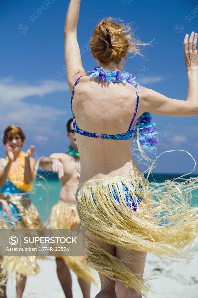 Stock Photo: 1574R-20596 Rear view of a young woman hula dancing on the beach