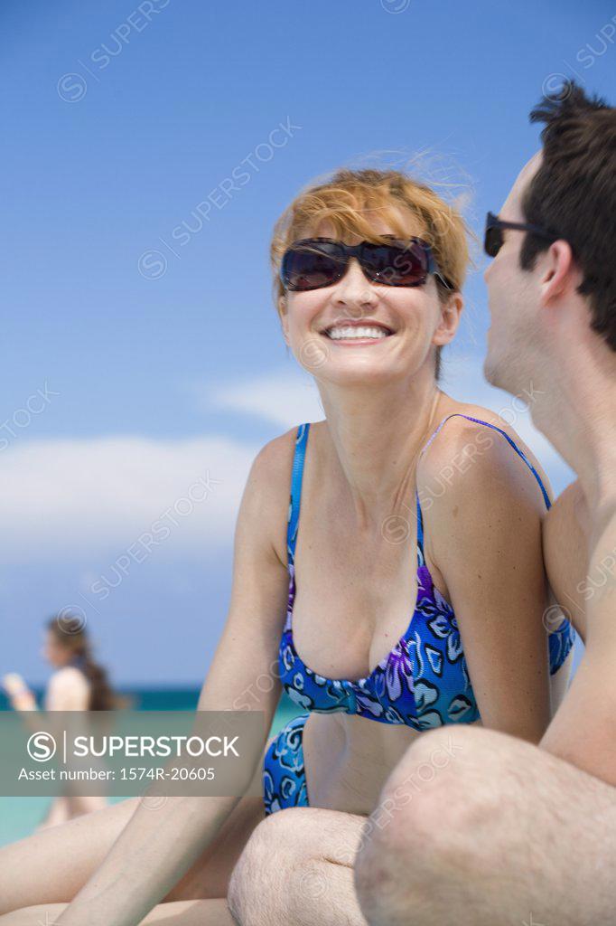 Stock Photo: 1574R-20605 Side profile of a young couple sitting on the beach