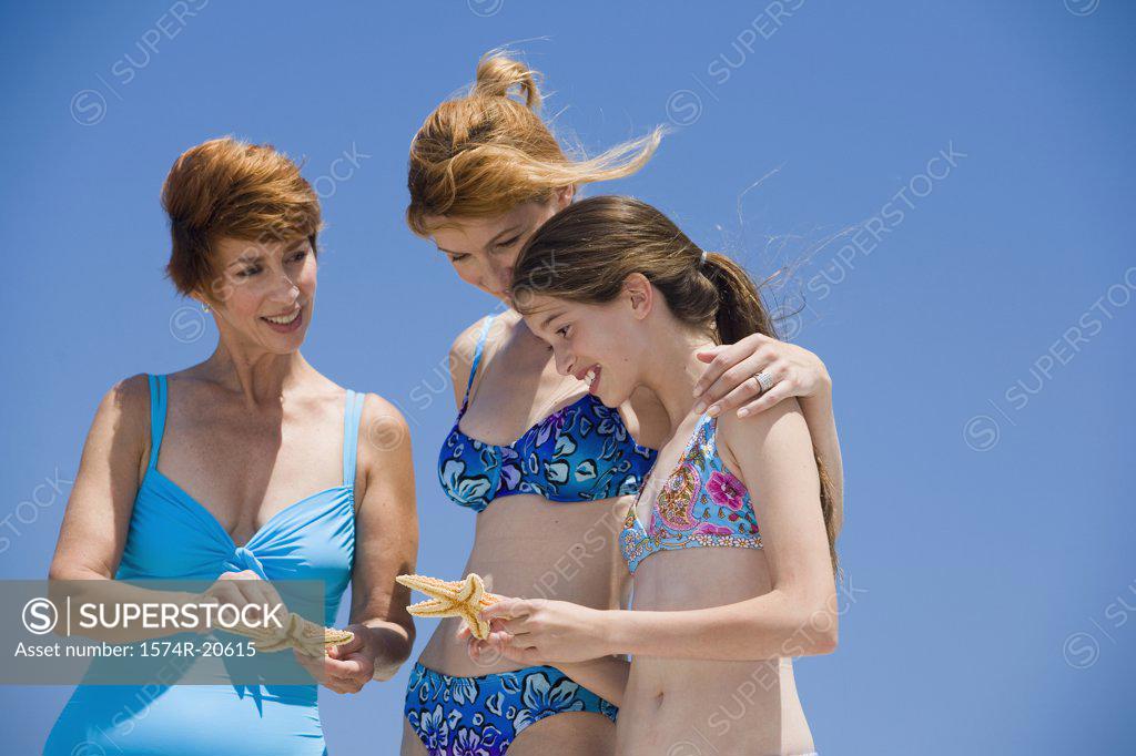 Stock Photo: 1574R-20615 Side profile of a girl standing with her mother and grandmother looking at starfish