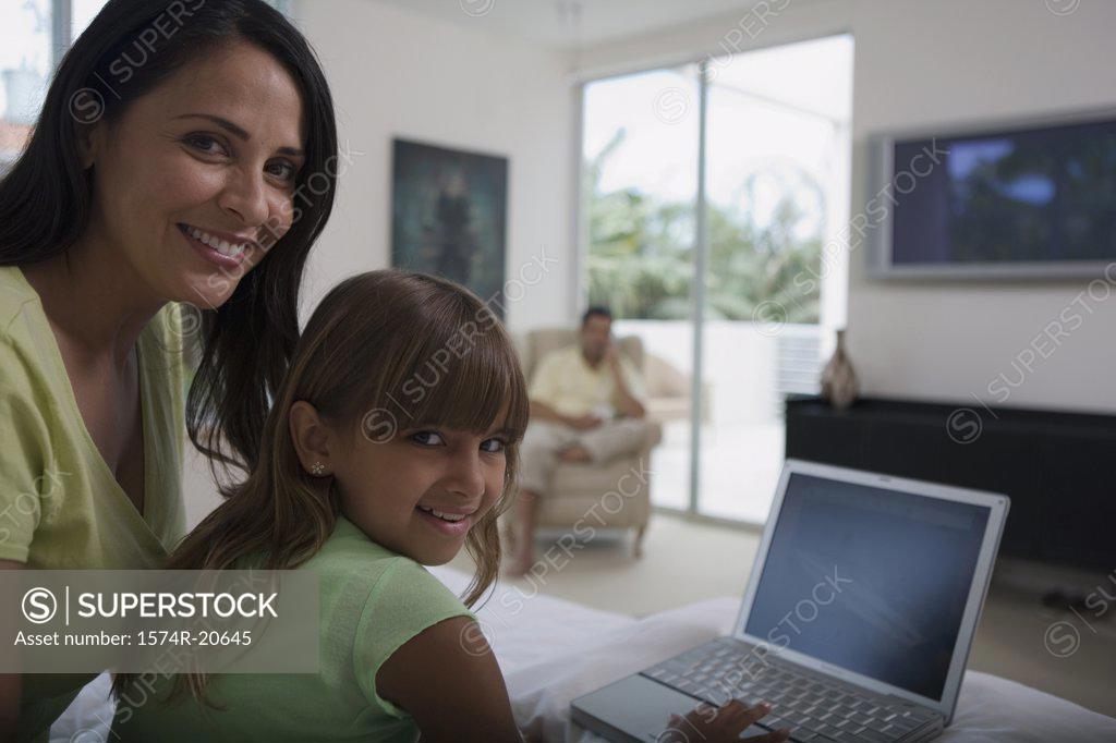 Stock Photo: 1574R-20645 Portrait of a girl using a laptop with her mother sitting behind her