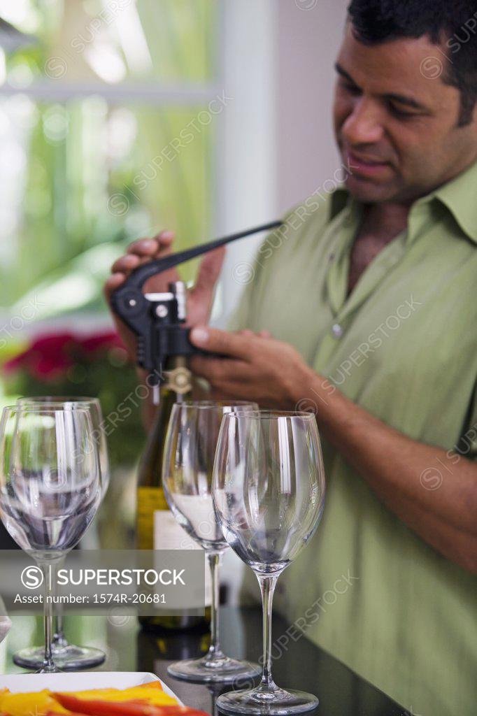 Stock Photo: 1574R-20681 Side profile of a mature man unscrewing the cork of a wine bottle