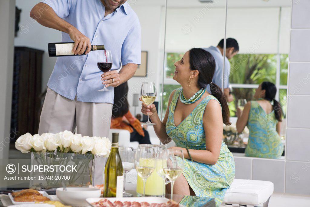 Stock Photo: 1574R-20700 Mature man pouring red wine into a wineglass and a mature woman looking at him