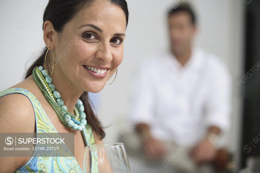 Stock Photo: 1574R-20719 Portrait of a mature woman smiling with a mid adult man sitting in the background
