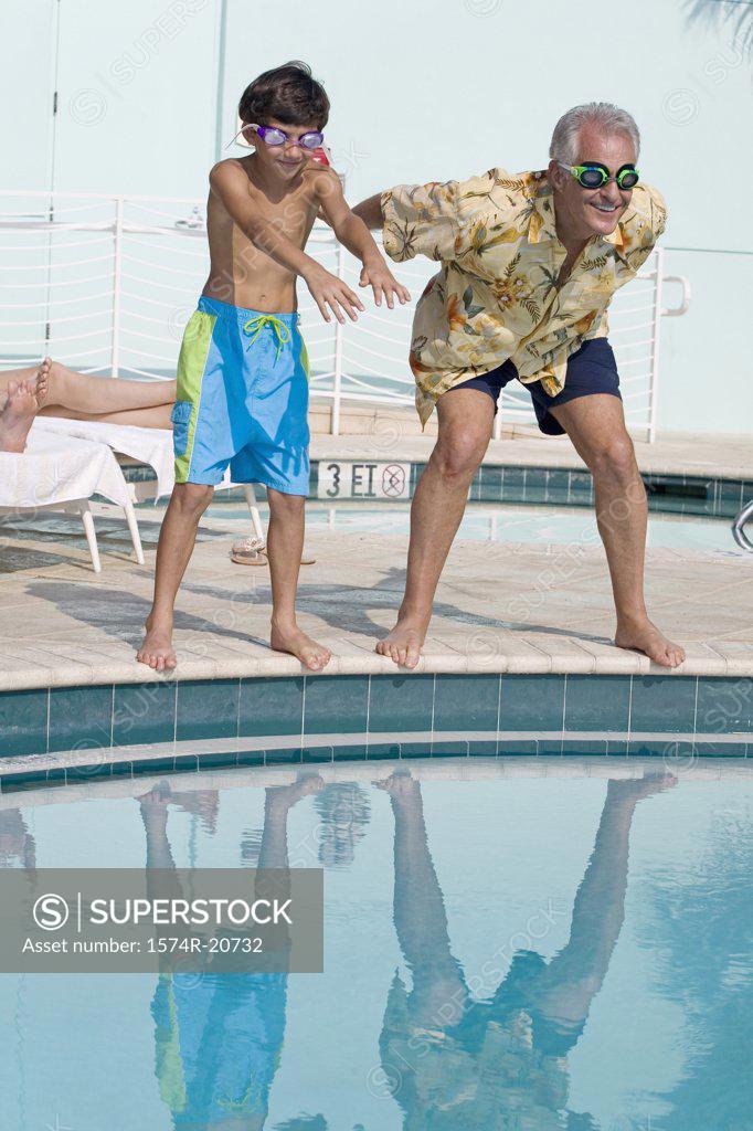 Stock Photo: 1574R-20732 Senior man teaching his grandson to swim at poolside