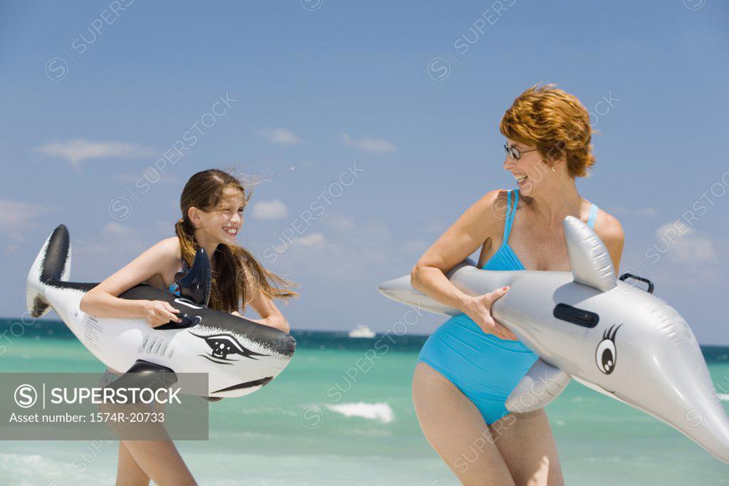 Stock Photo: 1574R-20733 Senior woman playing with her granddaughter holding fish shaped floats on the beach