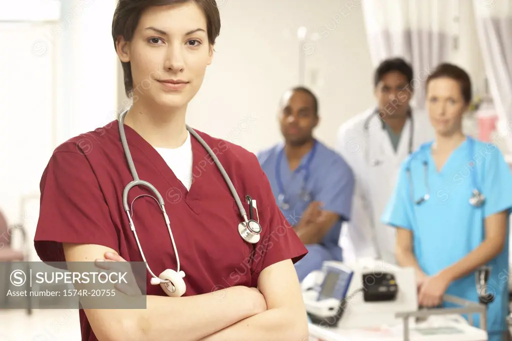 Portrait of a female doctor standing with her arms crossed and her colleagues in the background