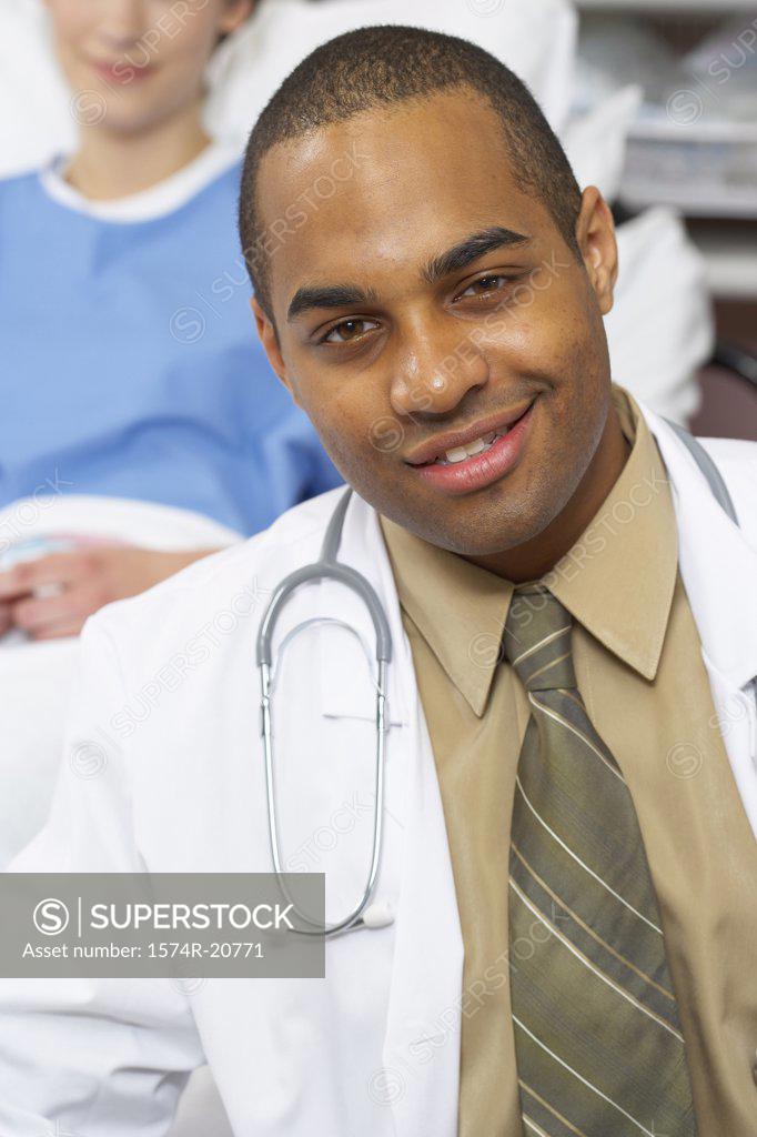 Stock Photo: 1574R-20771 Portrait of a male doctor smiling with a female patient reclining on the bed behind him