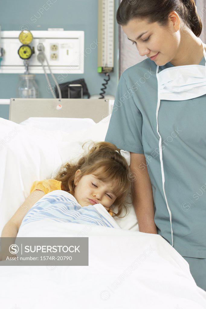 Stock Photo: 1574R-20790 Girl sleeping on the bed and a female nurse standing beside her