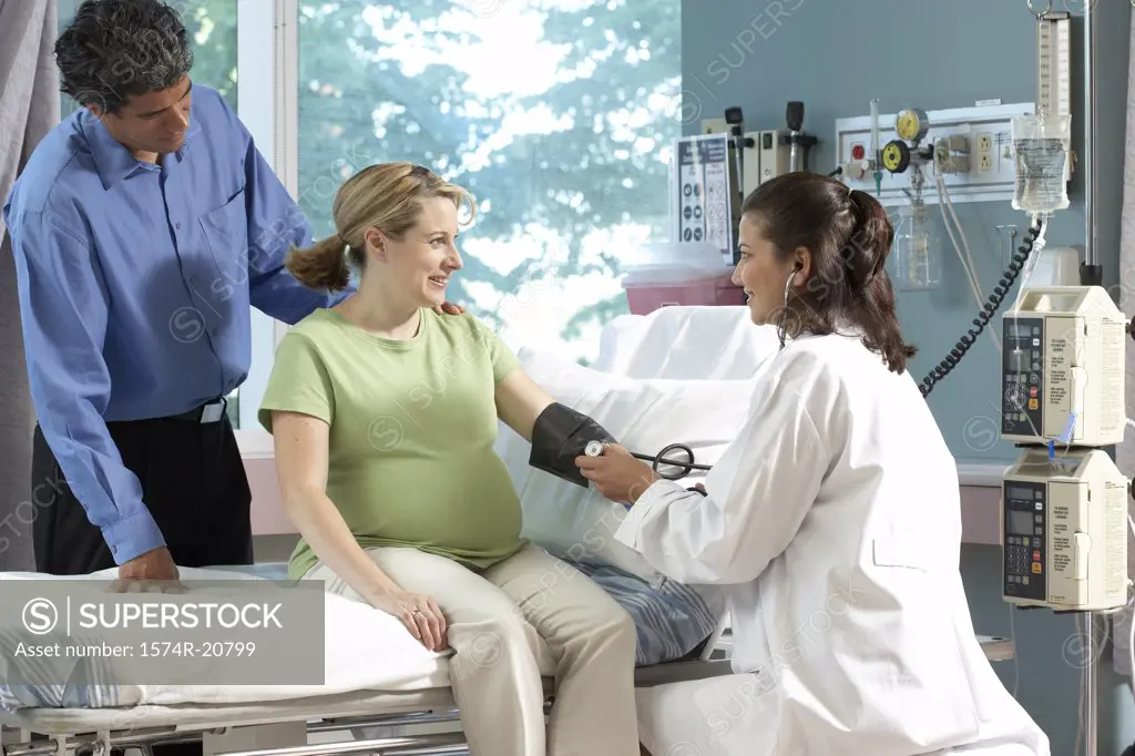 Side profile of a female doctor checking the blood pressure of a pregnant woman