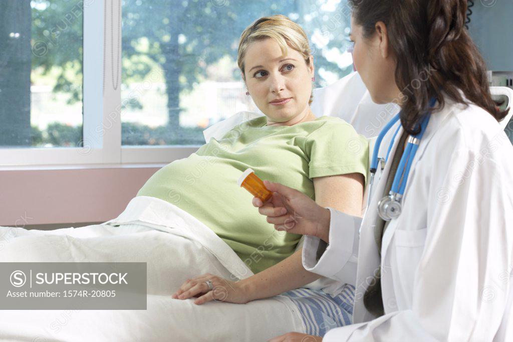 Stock Photo: 1574R-20805 Side profile of a female doctor giving a bottle of pills to a pregnant woman