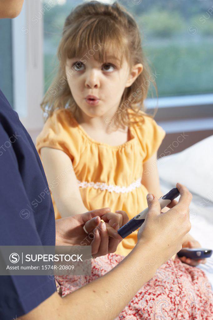 Stock Photo: 1574R-20809 Mid section view of a female nurse taking a blood sample from a girl's finger