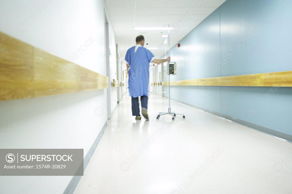 Stock Photo: 1574R-20829 Rear view of a male patient walking with an IV drip stand
