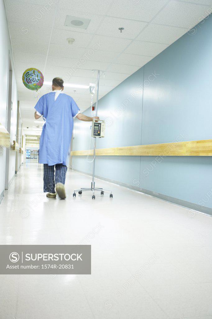 Stock Photo: 1574R-20831 Rear view of a male patient walking with an IV drip stand