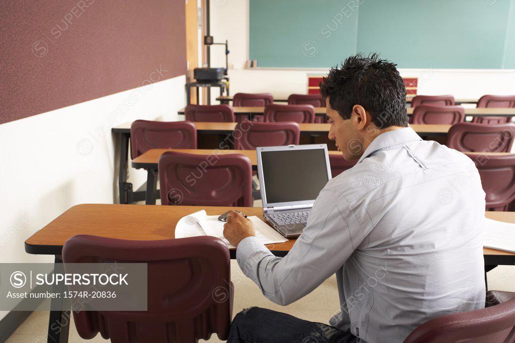 Stock Photo: 1574R-20836 Rear view of a college student sitting in a lecture hall in front of a laptop