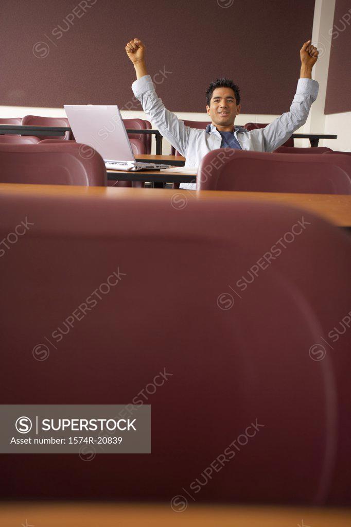 Stock Photo: 1574R-20839 College student sitting in a lecture hall with his arms raised