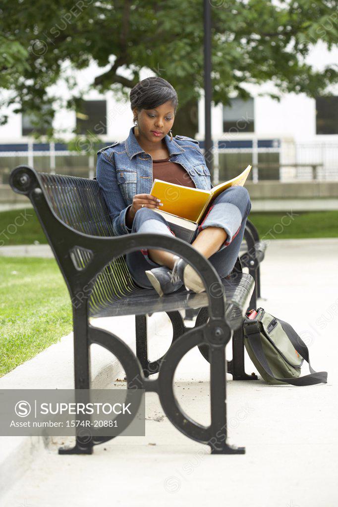 Stock Photo: 1574R-20881 College student sitting on a bench and reading a book