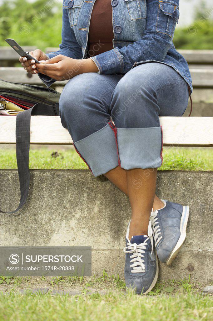 Stock Photo: 1574R-20888 Low section view of a college student using a mobile phone