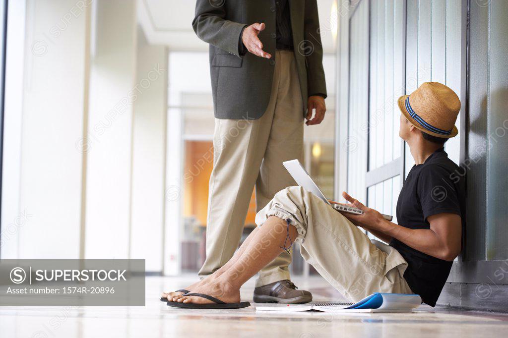 Stock Photo: 1574R-20896 Side profile of a college student sitting in a corridor and looking at a professor