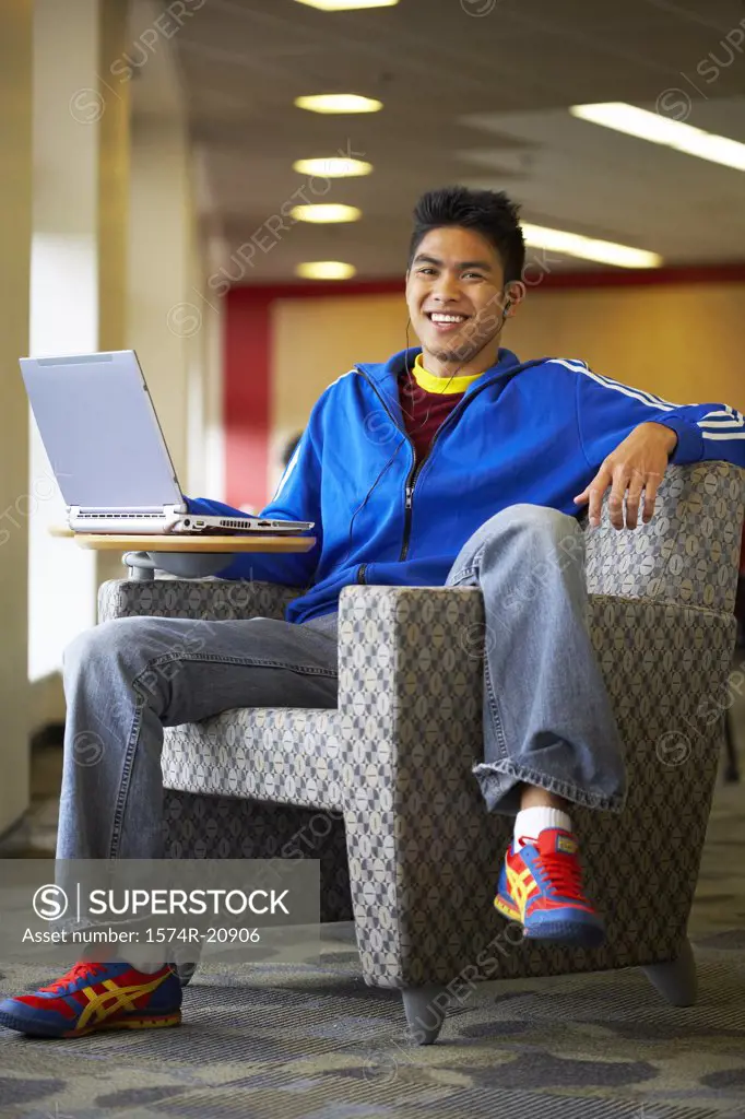 College student sitting in an armchair with a laptop