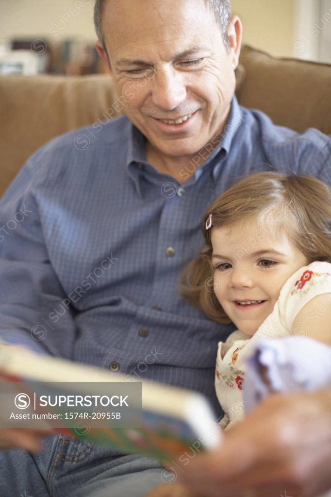 Stock Photo: 1574R-20955B Close-up of a girl sitting with her grandfather and reading a book