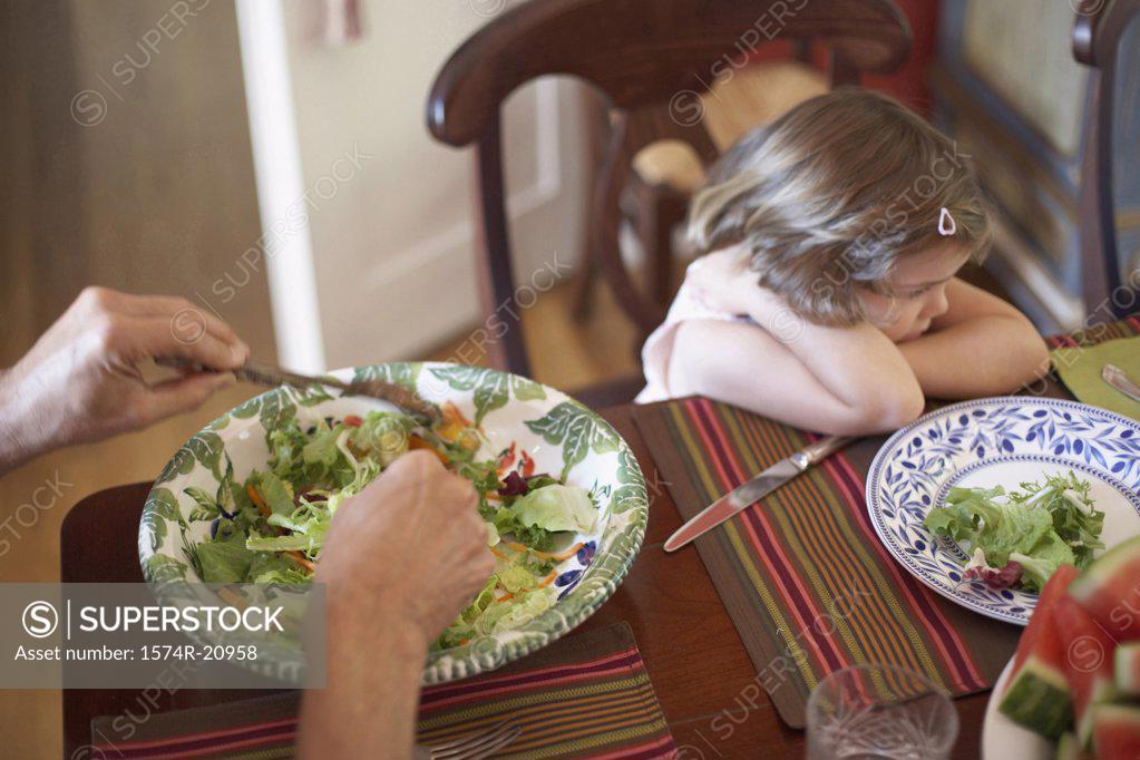 Stock Photo: 1574R-20958 High angle view of a girl sitting at a dining table looking displeased