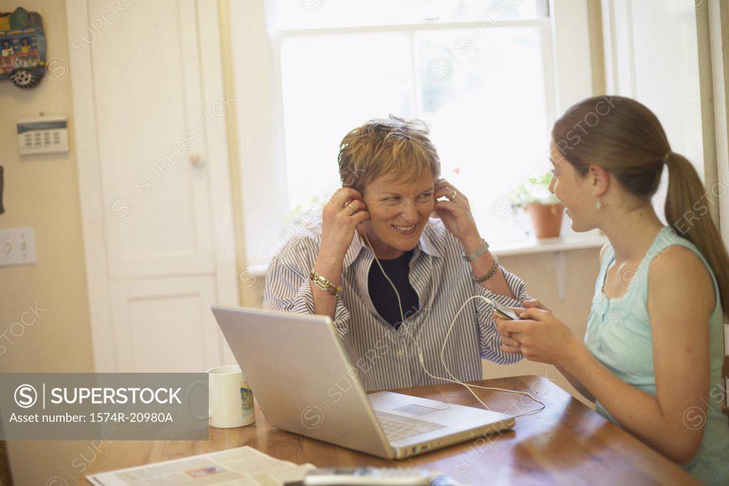 Stock Photo: 1574R-20980A Close-up of a mature woman wearing headphones with her granddaughter sitting beside her