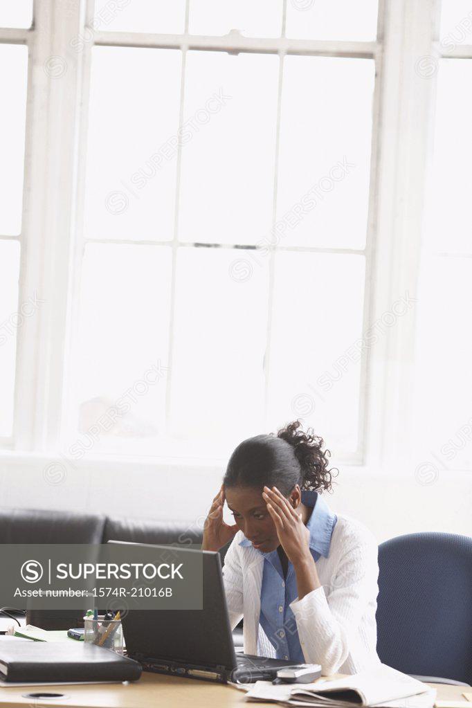 Stock Photo: 1574R-21016B Businesswoman sitting in an office with her hands on her forehead