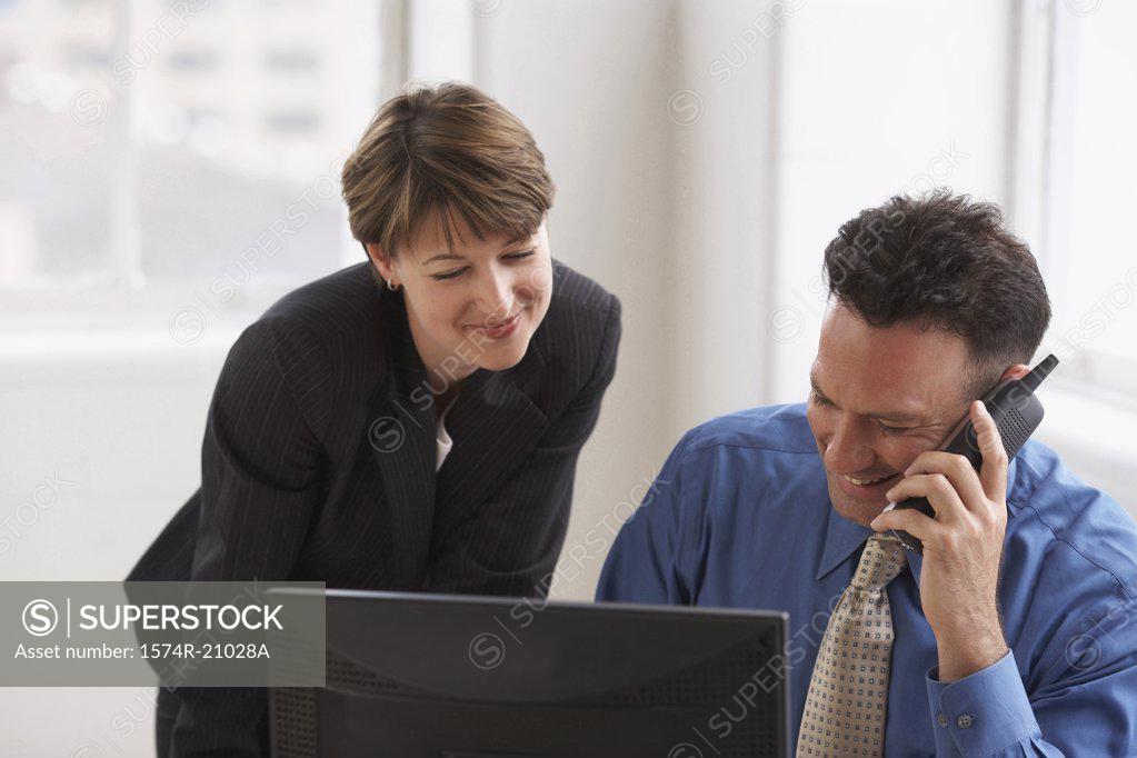 Stock Photo: 1574R-21028A Close-up of a businessman talking on the phone with a businesswoman standing beside him