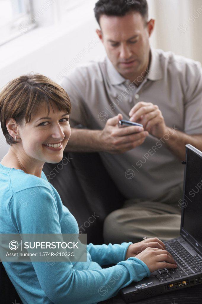 Stock Photo: 1574R-21032C Businesswoman working on a laptop with a businessman using a PDA