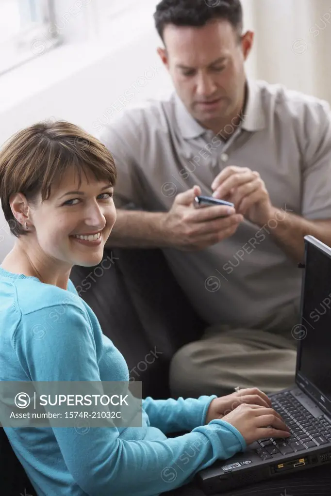 Businesswoman working on a laptop with a businessman using a PDA